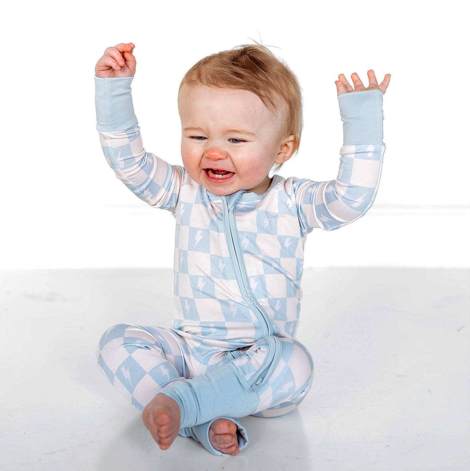 Baby wearing a blue and white checkered outfit on a white background