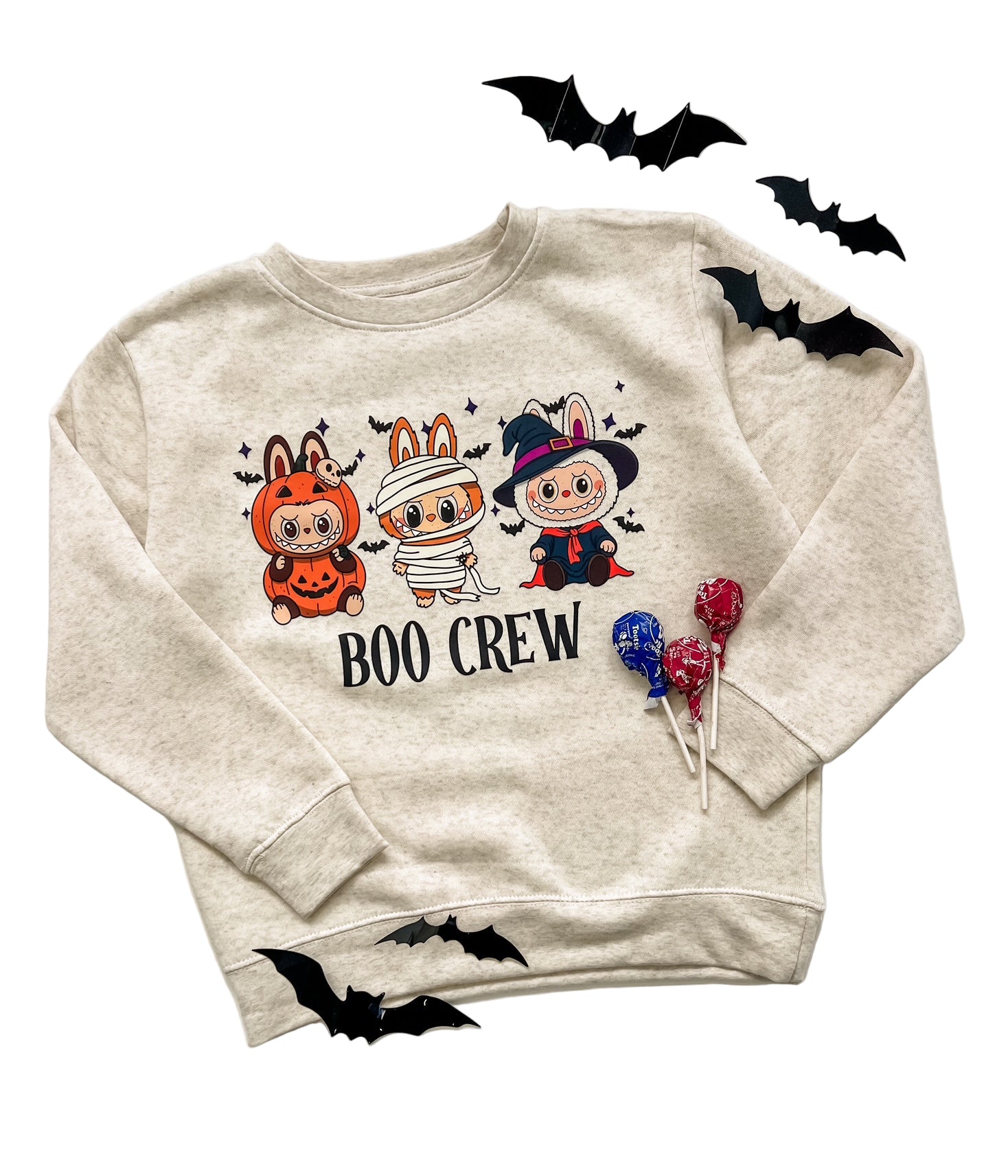 Beige sweatshirt with Halloween-themed design featuring cartoon characters and 'BOO CREW' text, surrounded by black bats and red lollipops on a white background.